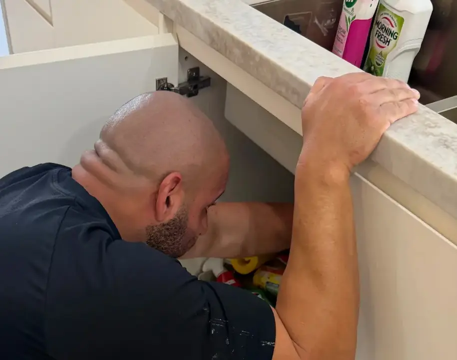 On Call Plumbing repairing a leaking pipe under a Canberra kitchen sink